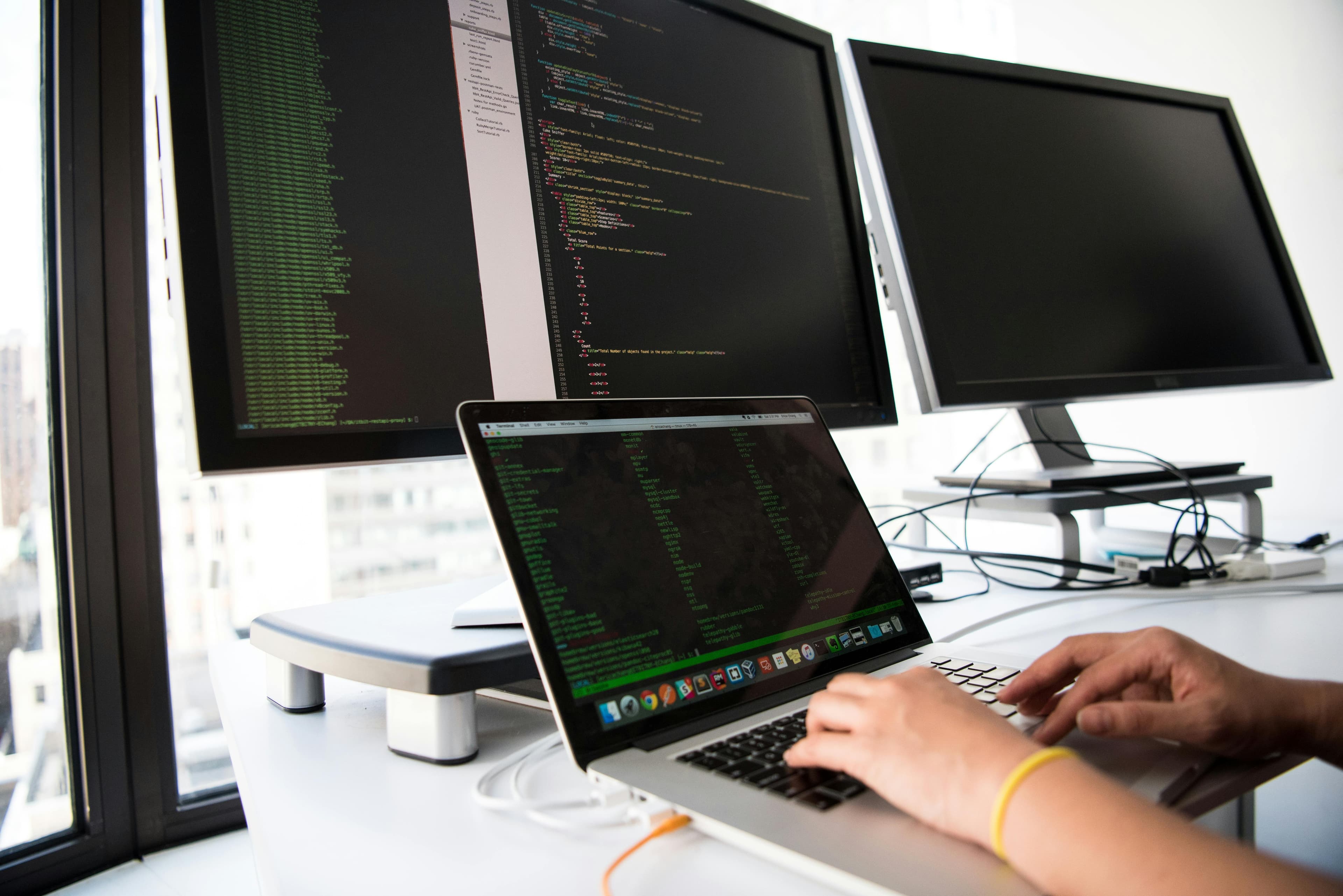 Engineer writing code on a multi-monitor workstation